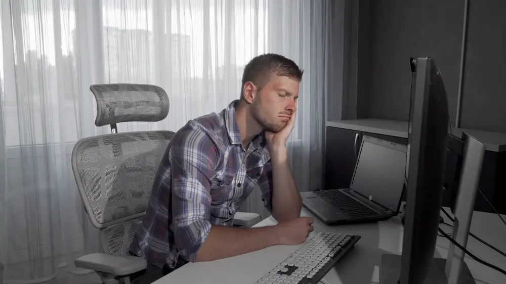 a young man who is sleeping in front of computer